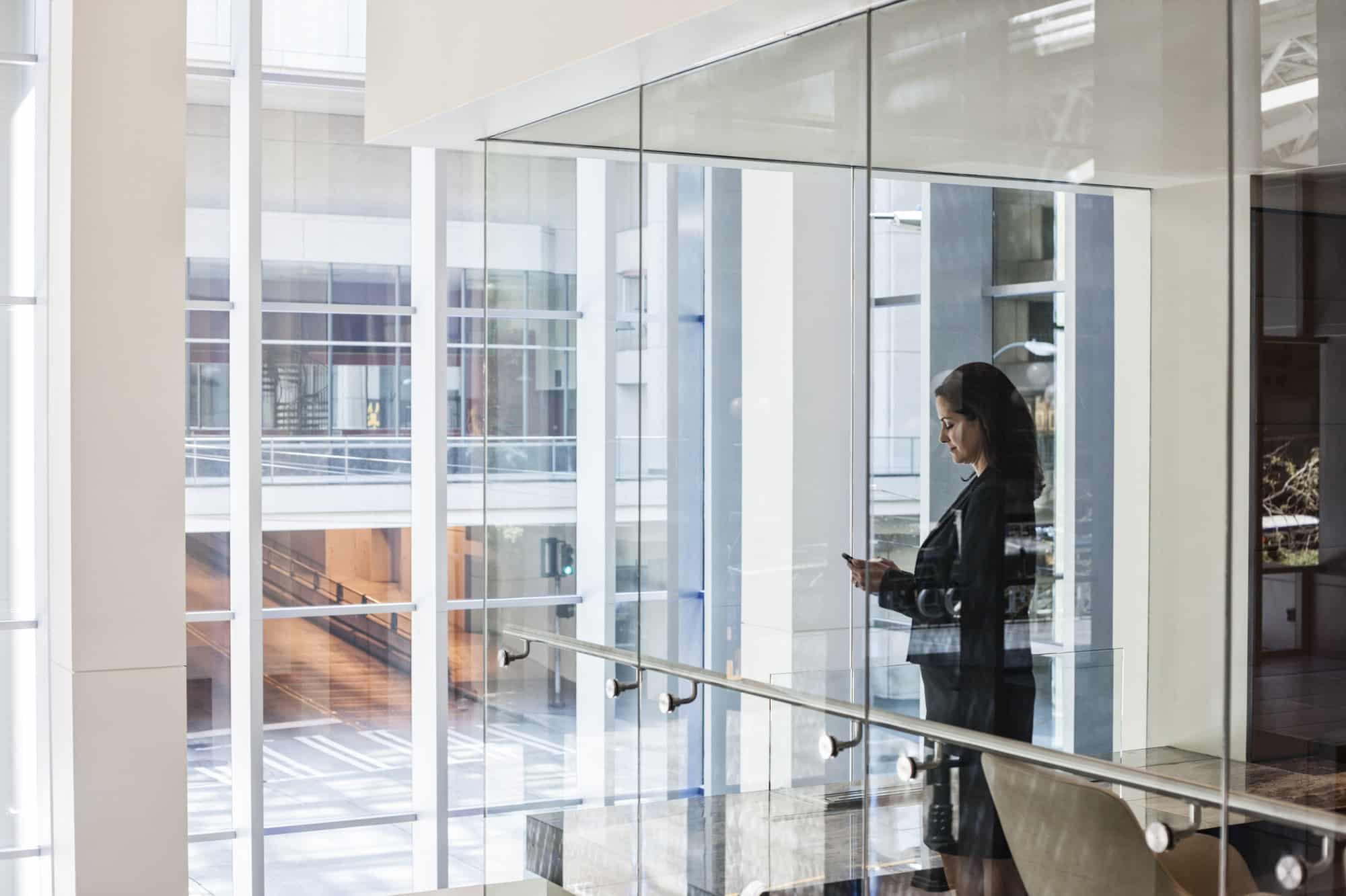 Businesswoman standing in a conference room window in a large business center.